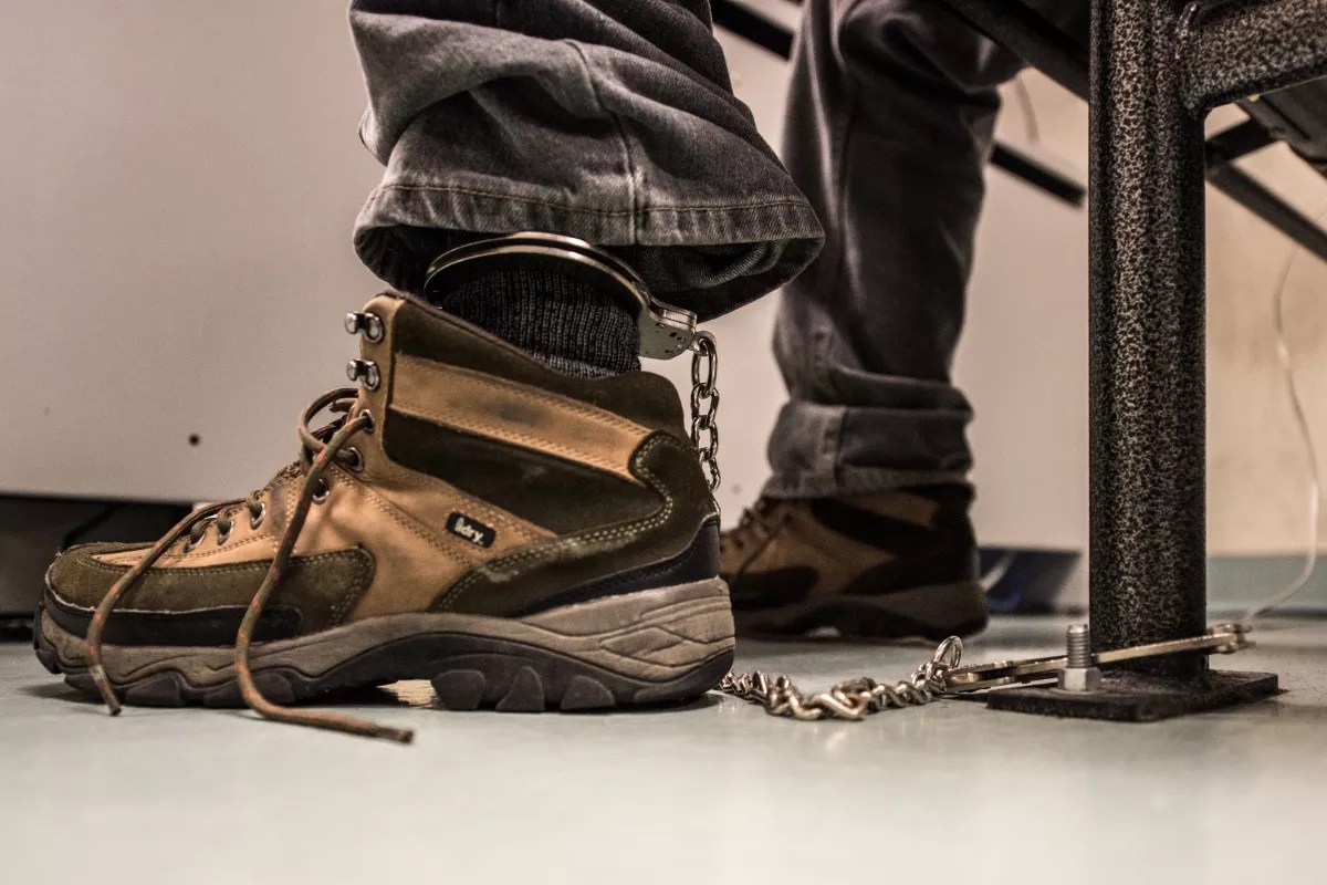 A photo of a detainee handcuffed to a bench.