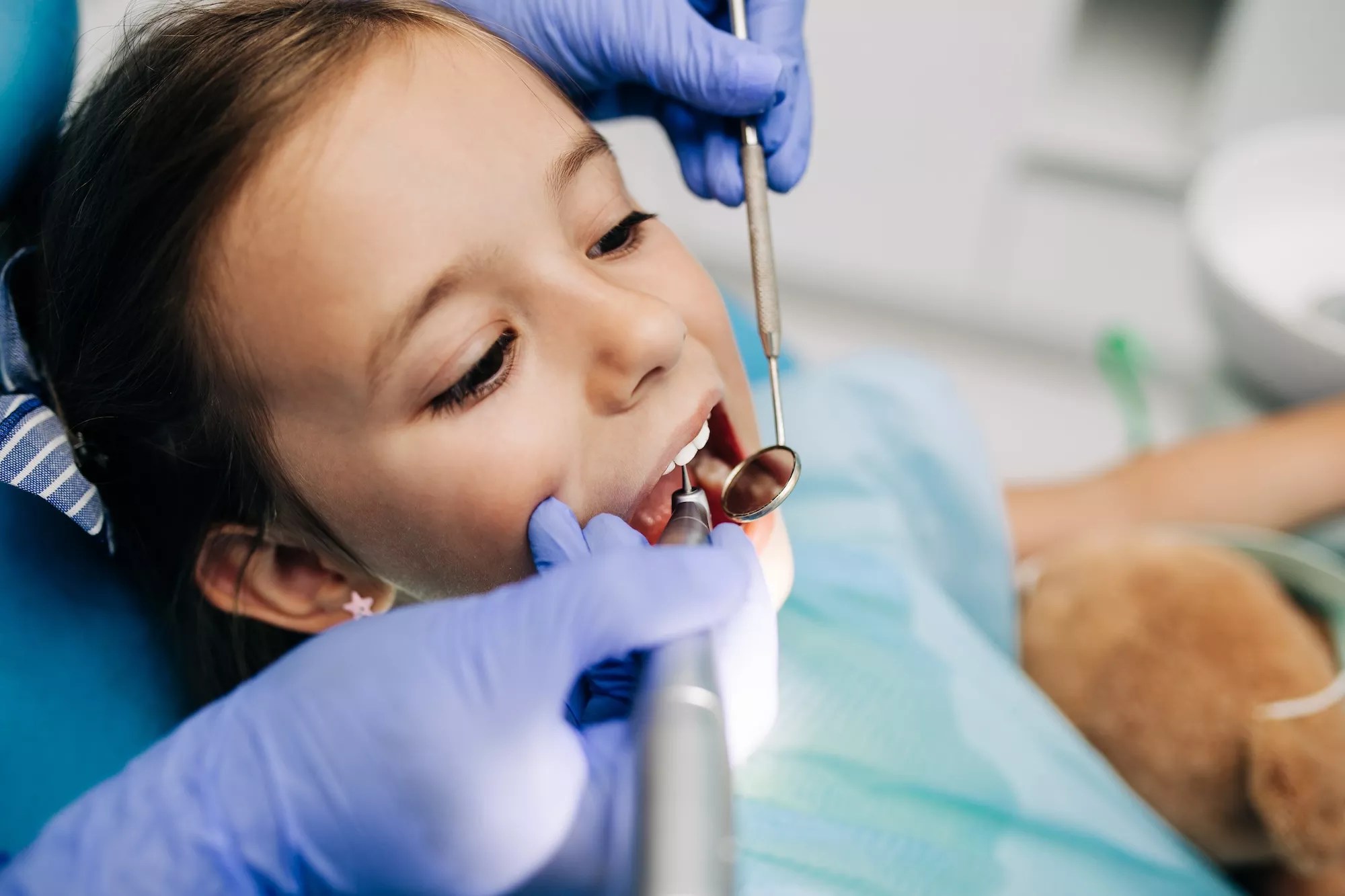 Cute little girl sitting in a dental chair and receiving dental treatment.