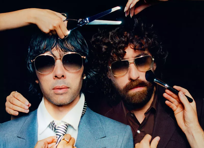 Two men are putting on makeup and getting a haircut