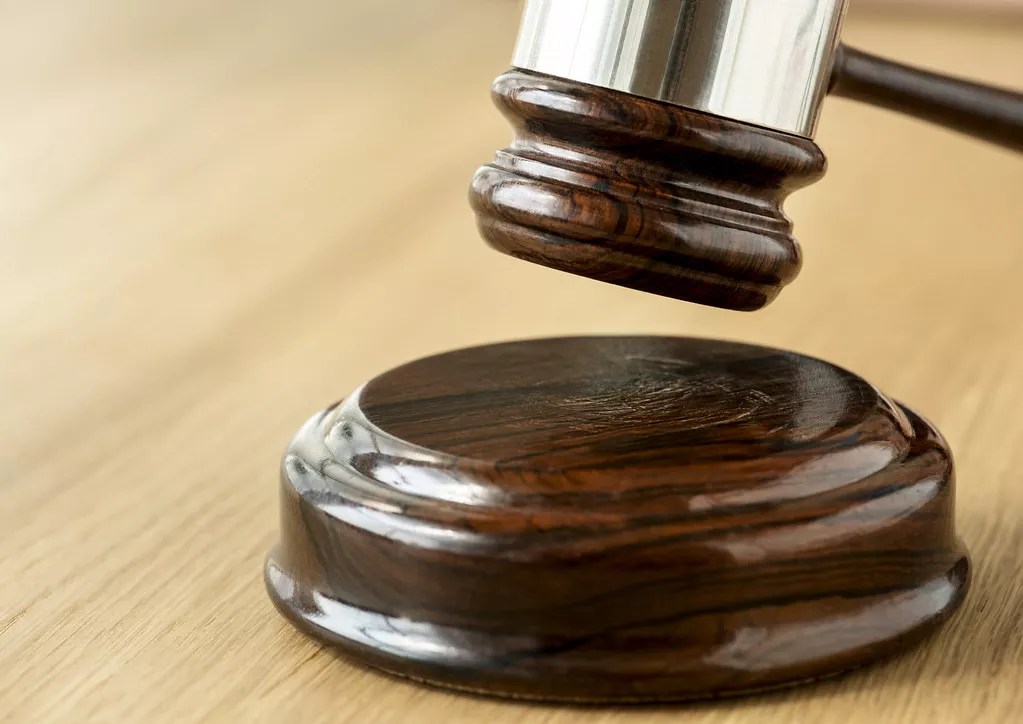 A judge's gavel hangs above a wooden surface.