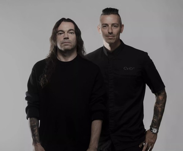 Two men posing for the camera wearing black.