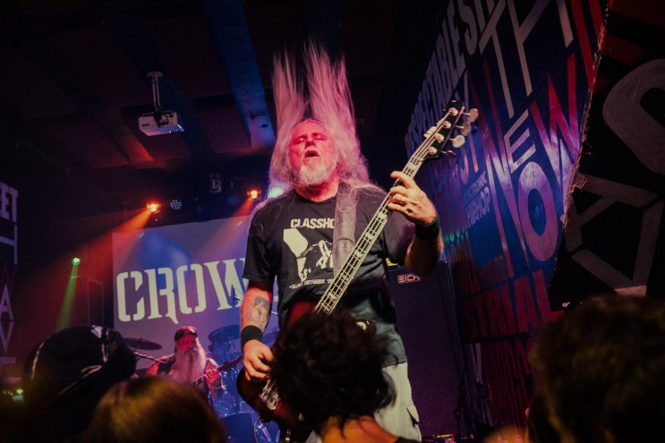 Bass player of a metal band performing in front of a crowd.
