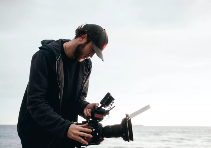 Man filming by the ocean.