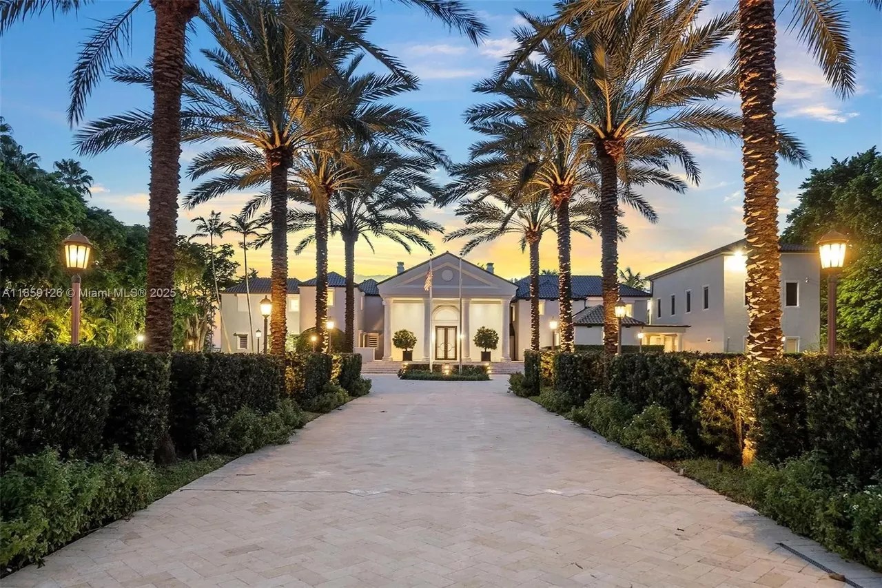 A brick driveway is pictured in the foreground leading to a luxe mansion in Miami Beach.
