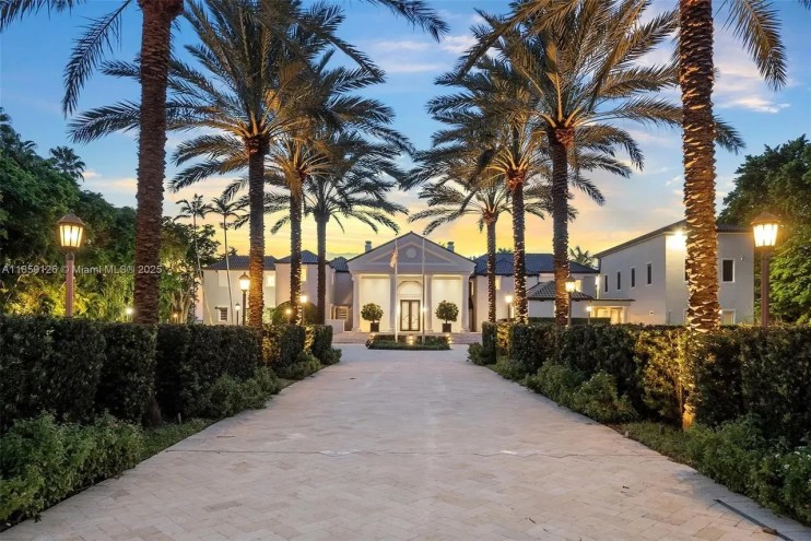 A brick driveway is pictured in the foreground leading to a luxe mansion in Miami Beach.