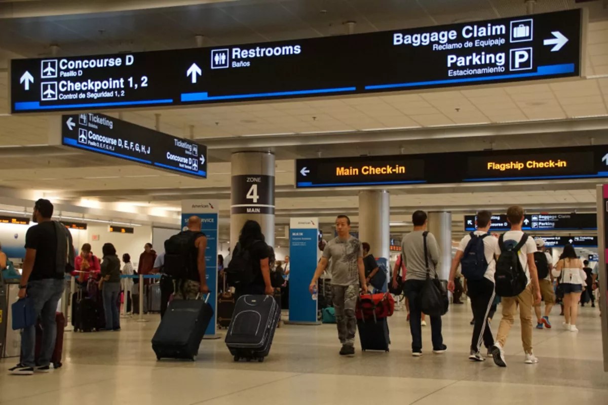 A photo of passengers with luggage inside Miami International Airport.