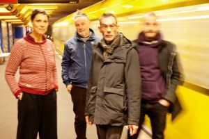 Picture of a four-piece band posing by a subway.