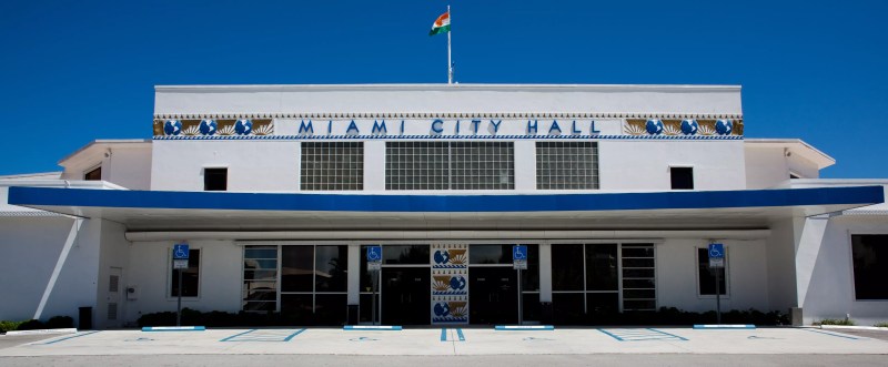 Depicted is Miami City Hall, a white and blue building, on a sunny day.
