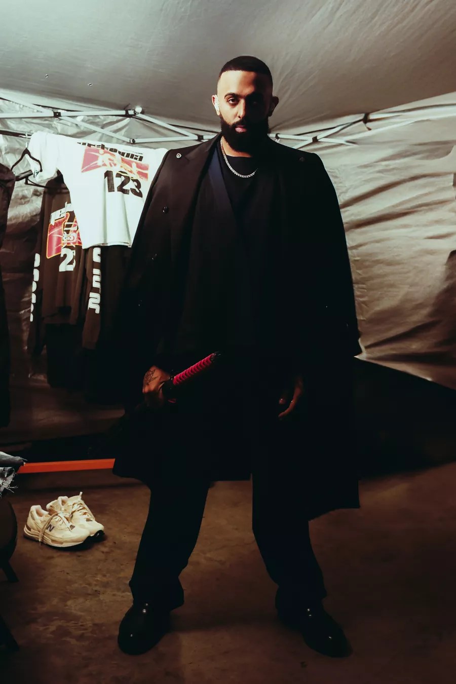 Picture of a man looking at the camera, wearing black, and holding a katana.