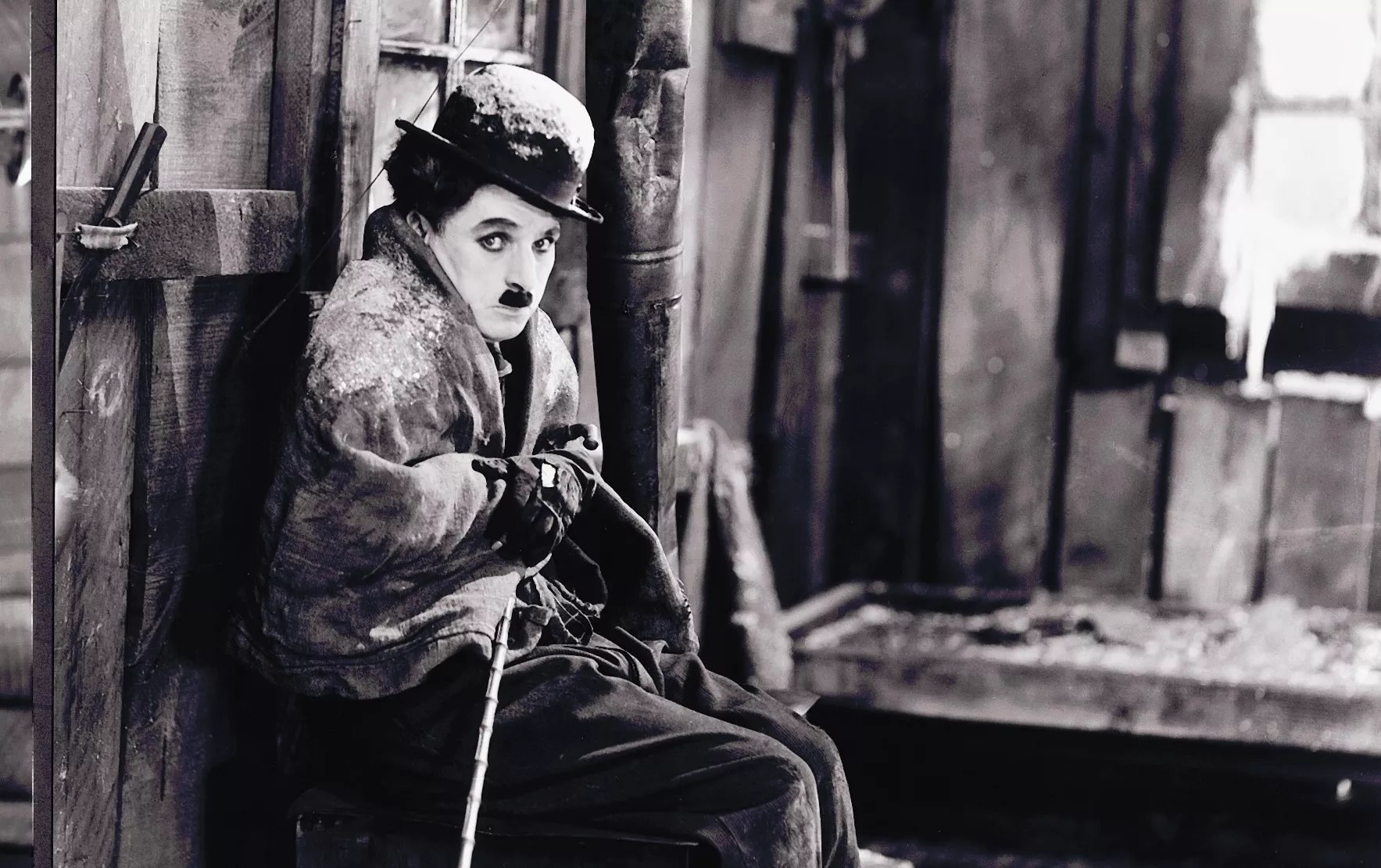 black-and-white film still of Charlie Chaplin wrapped in a blanket with snow on his hat and shoulders